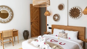 A bedroom with a wooden bed, a desk, and a wicker lamp. - Dzen Greenfield Villa 7 (Pejeng)