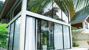 A modern house with large windows, a swimming pool, and lush greenery. - Dzen Greenfield Villa 7 (Pejeng)