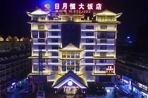 A multi-story hotel with a traditional architectural design, featuring a prominent entrance with a decorative roof. - Riyueheng Hotel (Hezhou)