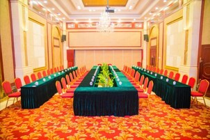 Un salón de conferencias con una larga mesa, sillas rojas y piso alfombrado.