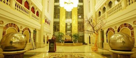A grand lobby with a central chandelier, ornate columns, and large decorative vases.