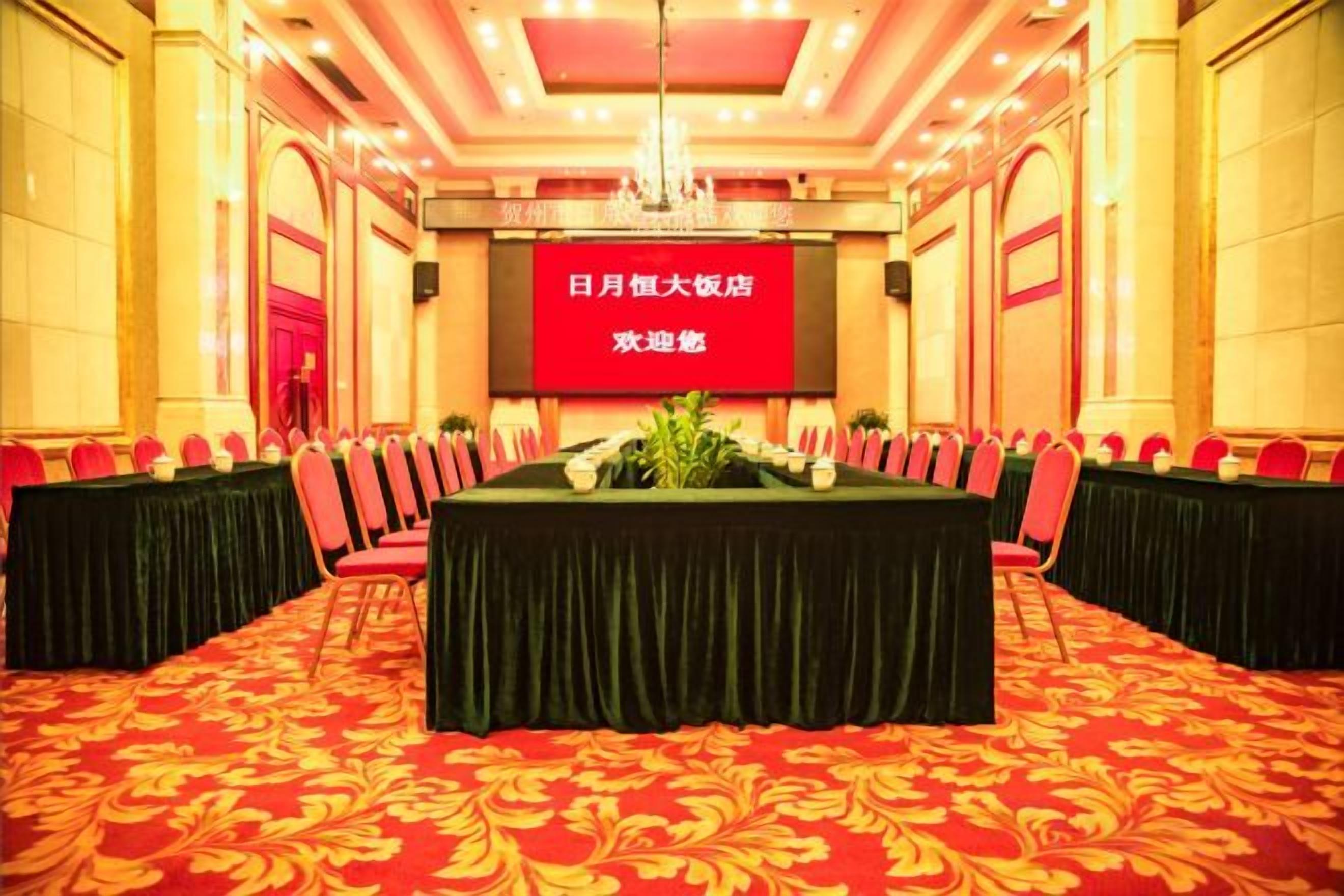 A conference room with a large screen, red chairs, and a table set for a meeting.