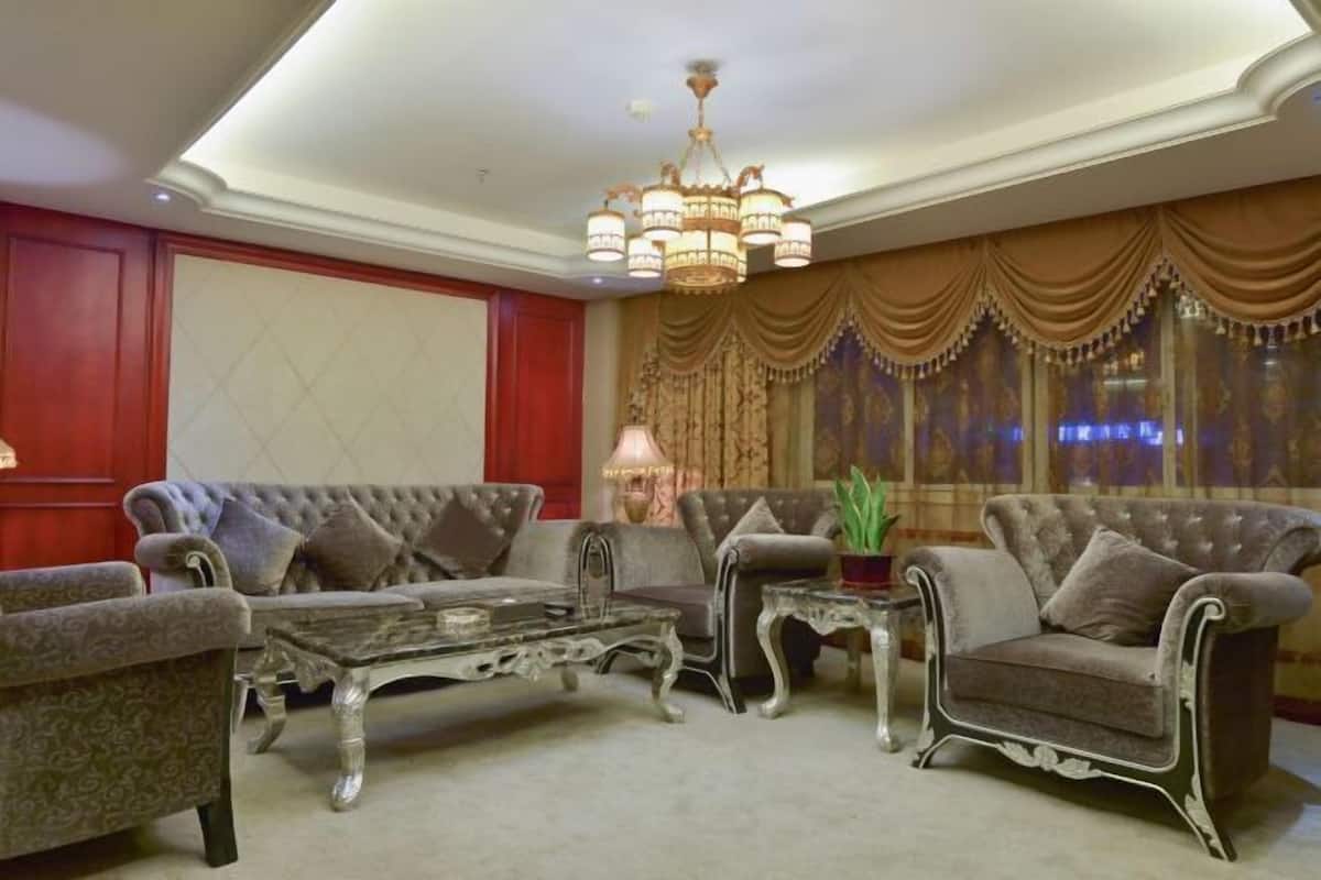 A room with a chandelier, two sofas, a coffee table, and a potted plant.