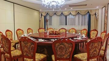 Une salle de conférence avec une table ronde, des chaises et un lustre.