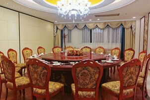 Un salón de conferencias con una mesa redonda, sillas y una araña.