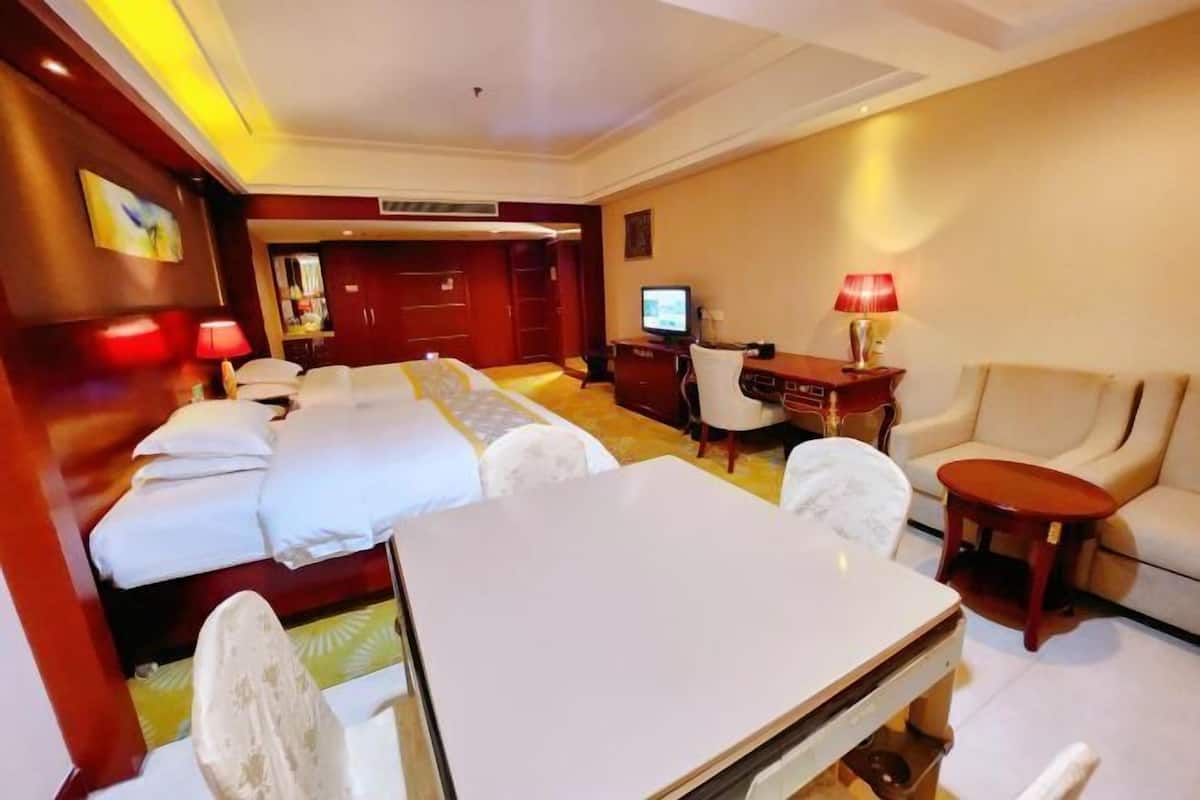 A hotel room with a bed, a desk, a chair, a TV, and a sofa.