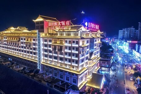 A multi-story hotel with illuminated signage, a prominent entrance, and a busy street in the background.. Riyueheng Hotel
