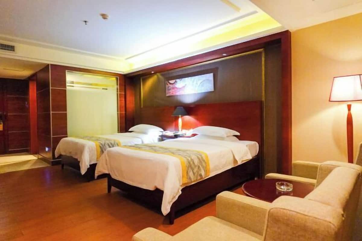 A hotel room with two beds, a desk, a chair, and a TV mounted on the wall.