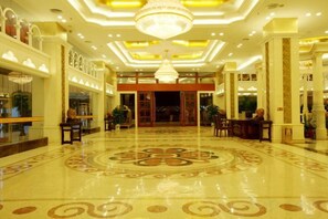 A spacious lobby with a polished floor, a grand chandelier, and a reception desk. - Riyueheng Hotel (Hezhou)