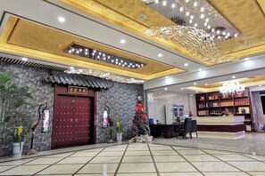 A hotel lobby with a reception desk, a large red door, and a decorative ceiling. - Riyueheng Hotel (Hezhou)