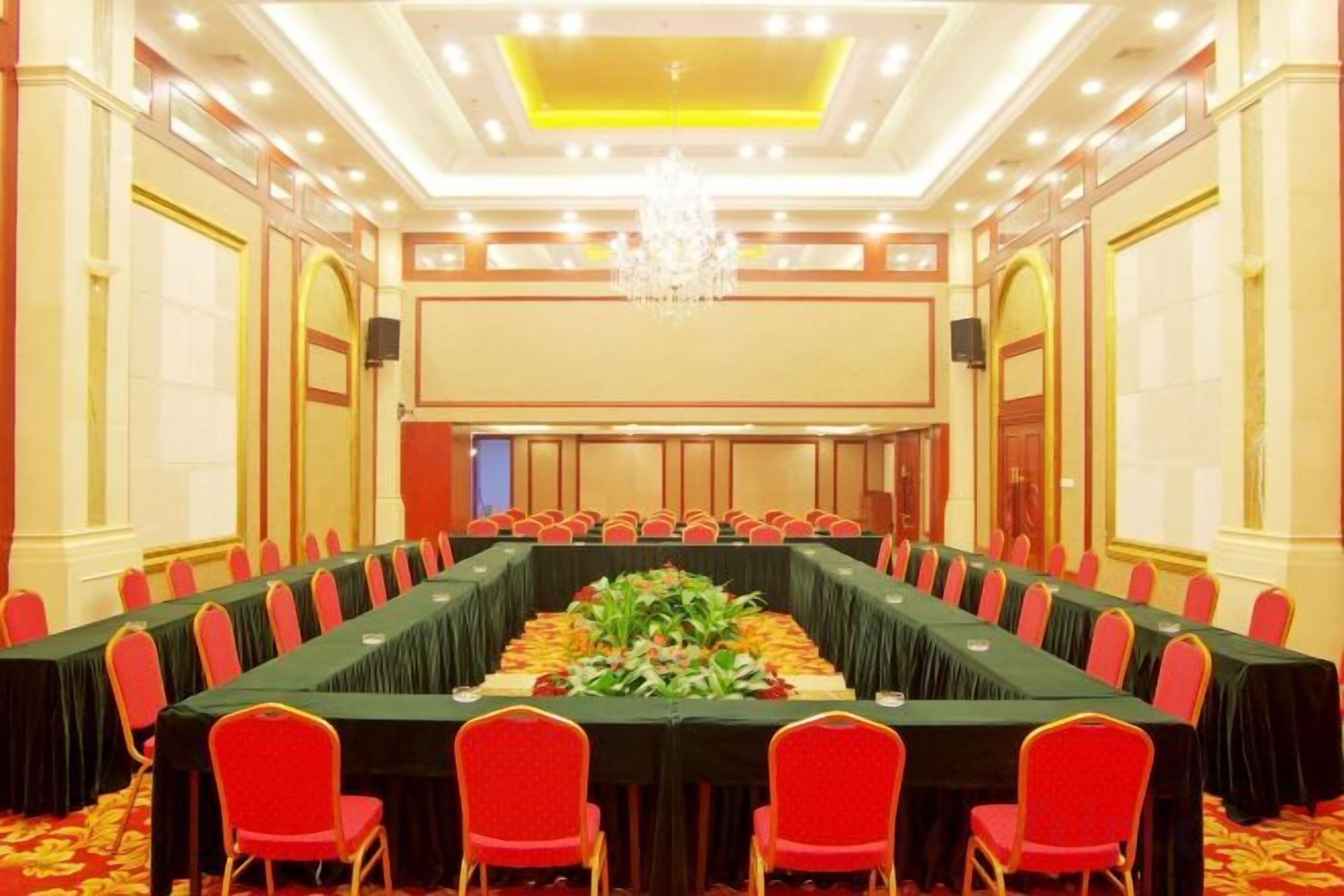 A conference room with a long table, red chairs, and a chandelier.