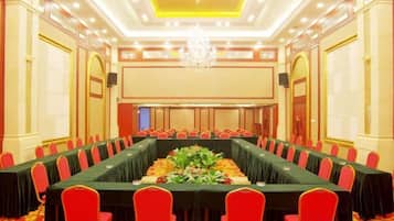 A conference room with a long table, red chairs, and a chandelier.