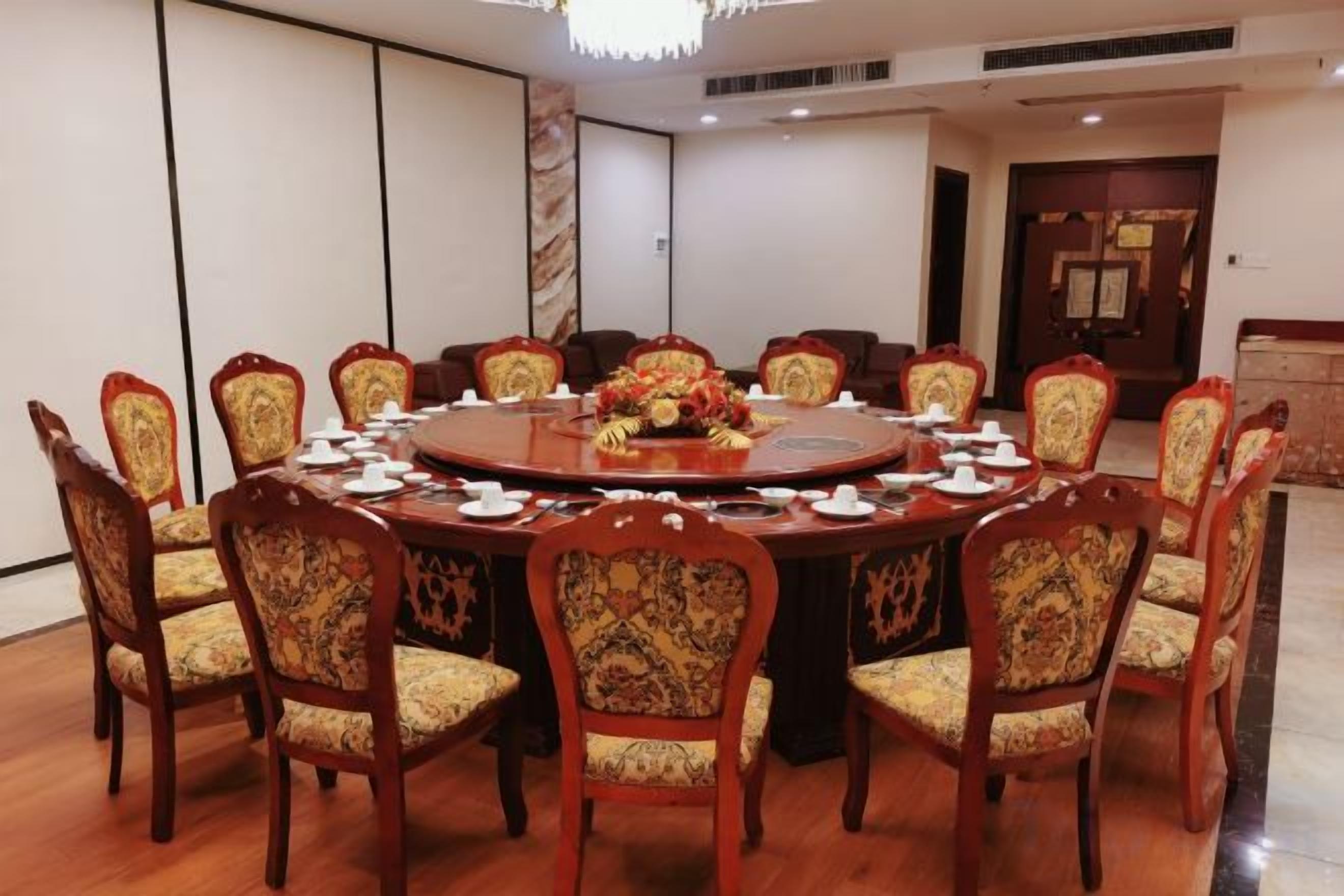 A conference room with a round table, chairs, and a floral centerpiece.
