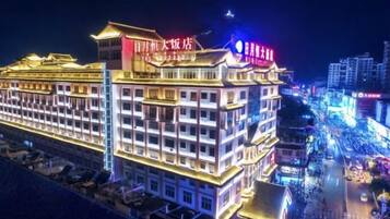 Un hotel de varios pisos con letreros iluminados, una entrada destacada y una calle concurrida al fondo.