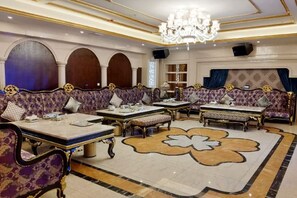 A luxurious hotel lobby with ornate sofas, a large floral carpet, and a chandelier. - Riyueheng Hotel (Hezhou)