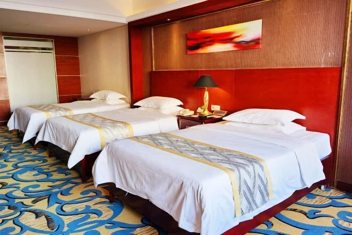 A hotel room with two beds, a red accent wall, a painting, and a patterned carpet.