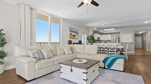 A living room with a sofa, a coffee table, and a view of the kitchen. - Gulf-front PCB Condo w/ Balcony, Resort Amenities, Game Room, Pools & Beach Gear Tortuga 1301 by Avantstay (Panama City Beach)