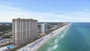 A coastal hotel with multiple floors, a beach with umbrellas, and a pier extending into the ocean. - Gulf-front PCB Condo w/ Balcony, Resort Amenities, Game Room, Pools & Beach Gear Tortuga 1301 by Avantstay (Panama City Beach)