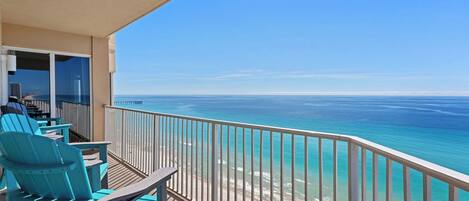 Un balcon avec des chaises turquoise et une vue sur l’océan.
