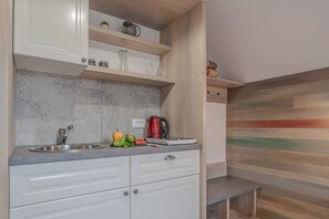 A kitchen with a stainless steel sink, white cabinets, and wooden shelves. - Lukec Homestead Adventure Studio Neža, Kostel, Slovenia (Kostel)