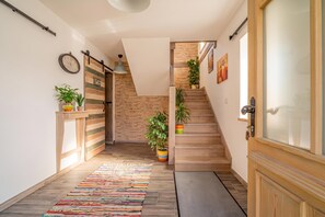 A modern interior with a wooden staircase, a colorful rug, and potted plants. - Lukec Homestead Adventure Studio Neža, Kostel, Slovenia (Kostel)
