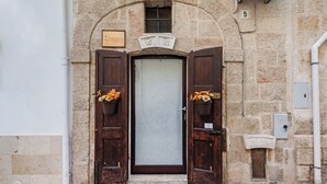 A stone building with a large arched doorway, two wooden doors, and a small window above the door. - Dimora Kiaorana In Polignano A Mare, Polignano a Mare, Italy (Polignano a Mare)