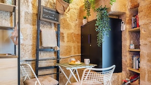 A cozy café with a stone wall, a black refrigerator, a small table with chairs, and a fire extinguisher. - Dimora Kiaorana In Polignano A Mare, Polignano a Mare, Italy (Polignano a Mare)