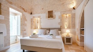 Una camera da letto con un letto grande, due comodini con lampade, una parete in pietra e una finestra.