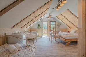 Ein gemütliches Schlafzimmer im Dachgeschoss mit geneigter Decke, einem Schreibtisch, einem Stuhl und einem Bett.