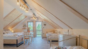 A cozy attic bedroom with two beds, a small table, and a chair.