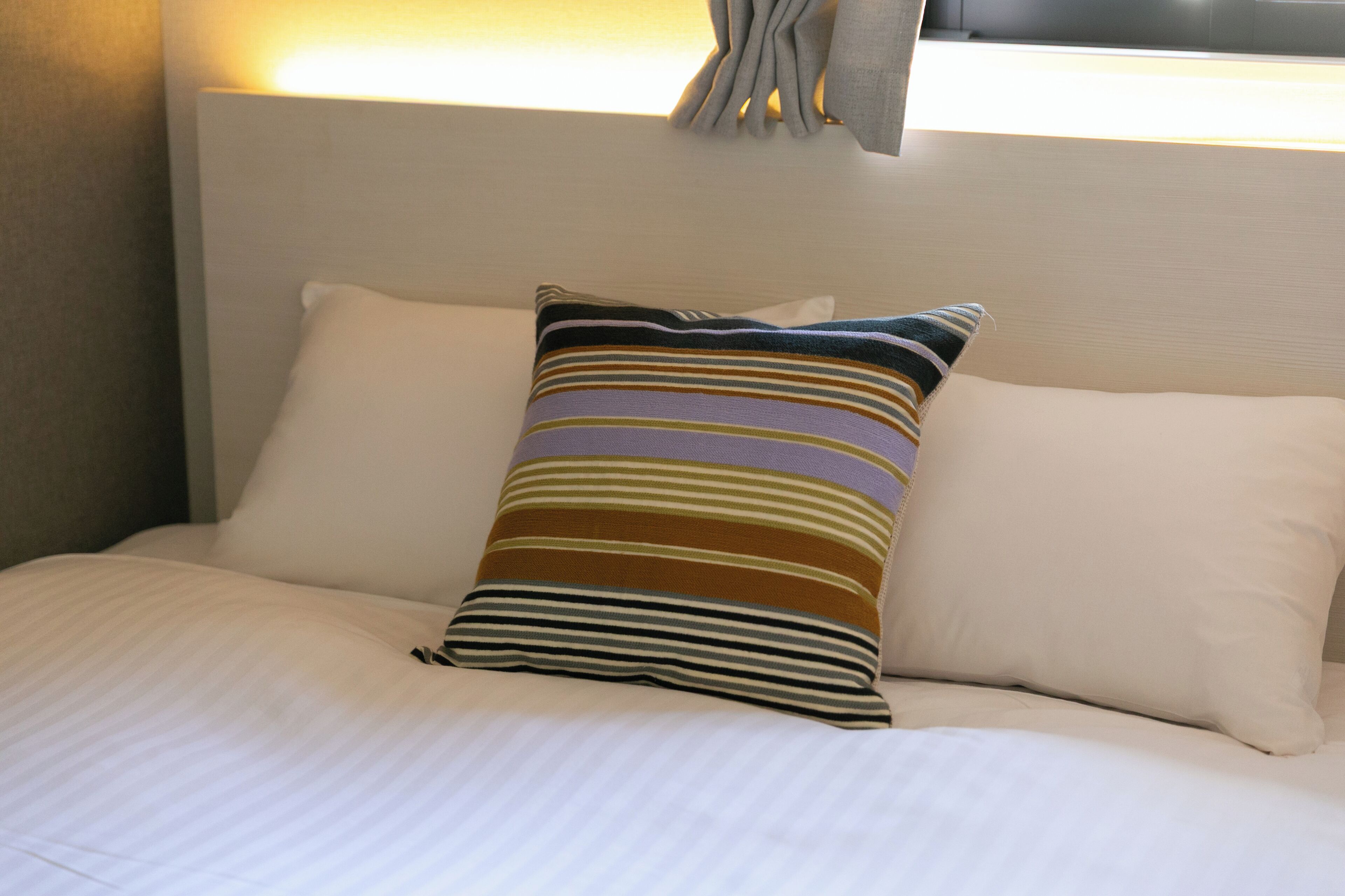 Un lit bien fait, avec du linge de lit blanc et des oreillers à rayures.