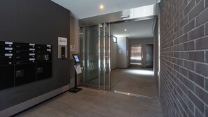 Un espace moderne pour les ascenseurs, doté d’un écran numérique, d’une boîte aux lettres et d’une porte en verre.