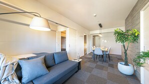 Un salon moderne avec un canapé gris, une lampe, une petite table et une plante en pot.