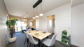 Un espace de salle à manger moderne avec une table en bois, des chaises grises et des luminaires suspendus.