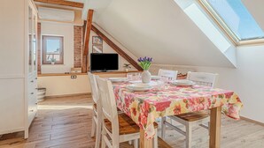 Un coin repas avec une table dressée pour quatre personnes, un téléviseur et une lucarne.