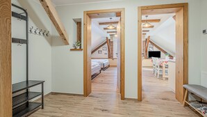 Un couloir avec des poutres en bois, une étagère en métal noir et un banc.