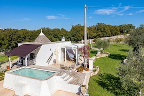 Ein Haus mit Swimmingpool, Sitzgelegenheit im Freien und einem Steinkamin.