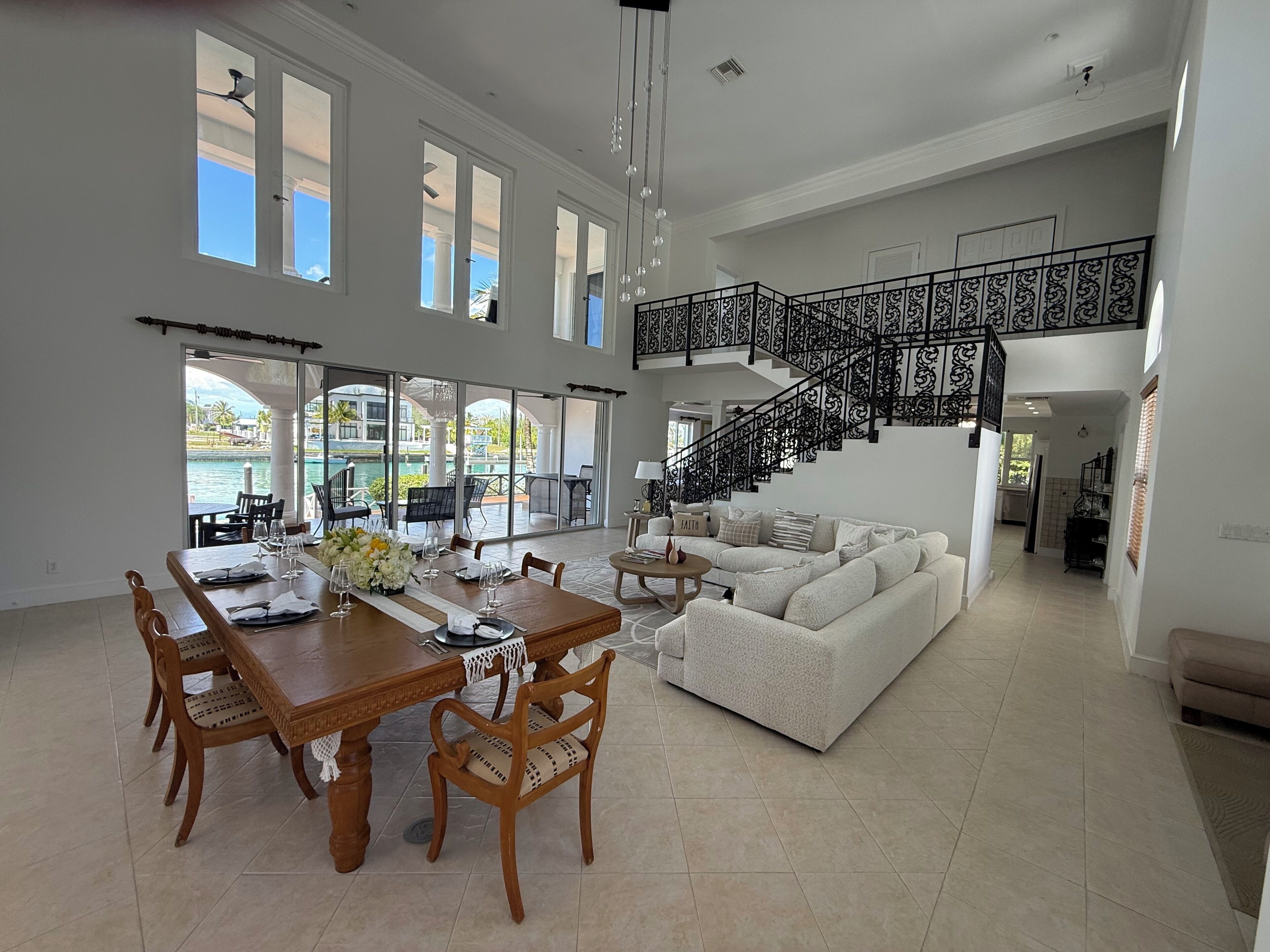A spacious living area with a dining table, chairs, a sofa, and a staircase.