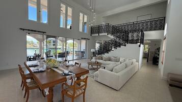 A spacious living area with a dining table, chairs, a sofa, and a staircase.