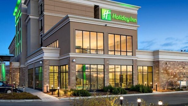 Un hotel Holiday Inn con un diseño moderno, amplias ventanas y una fachada bien iluminada.