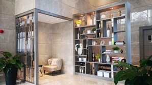 A modern interior with a large bookshelf, a seating area, and potted plants. - Mayfair Bangkok (Krung Thep Maha Nakhon)