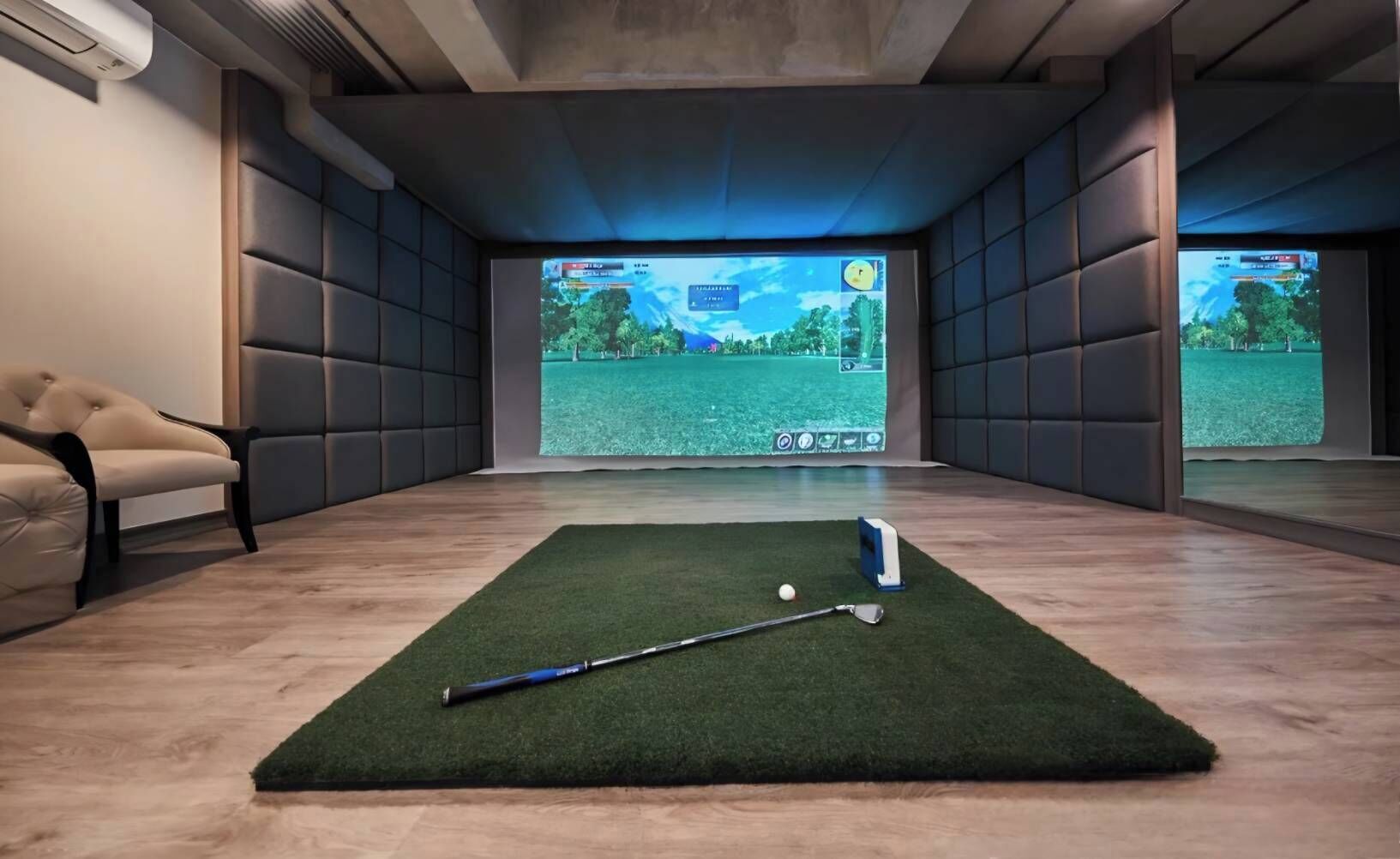 Une pièce dotée d’un espace recouvert de gazon synthétique vert, destiné à la pratique du golf, ainsi que d’un club de golf et d’une balle.