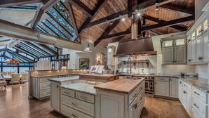 Cucina spaziosa con una grande isola, travi in legno e mobili bianchi.