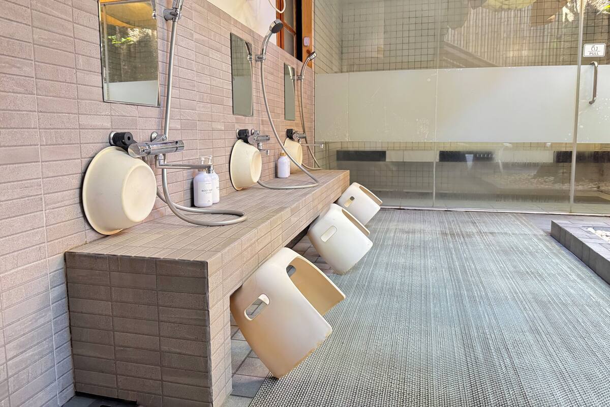 Een openbaar toilet met meerdere wasbakken, spiegels en handdrogers.