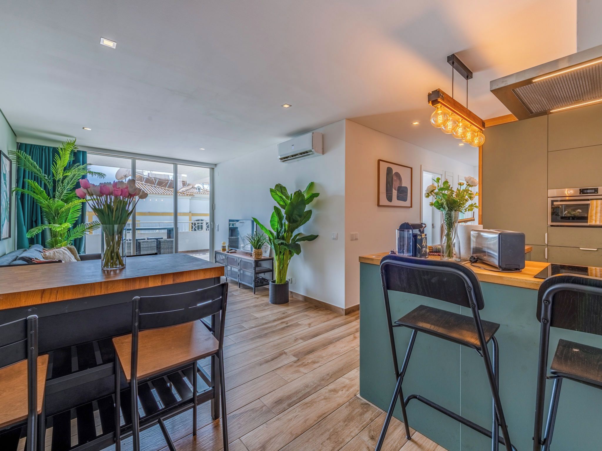 Une cuisine moderne dotée d’un îlot central, de tabourets de bar et d’un coin repas avec des chaises.