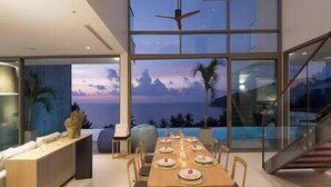 A modern dining area with a view of the ocean and a staircase leading to an upper level. - Malaiwana - Duplex (B2) by Elite Havens (A. Thalang)