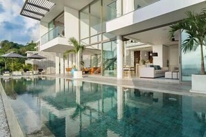 A modern pool area with clear water, a glass-enclosed lounge, and outdoor seating. - Malaiwana - Duplex (B2) by Elite Havens (A. Thalang)