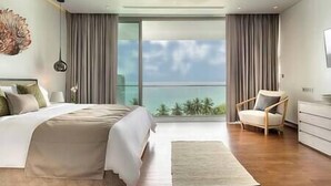 A modern bedroom with a large bed, a chair, and a view of the ocean through floor-to-ceiling windows. - Malaiwana - Duplex (B2) by Elite Havens (A. Thalang)