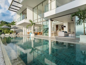 Et moderne poolområde med en klar pool, liggestole og en trappe der fører op til højere niveauer.