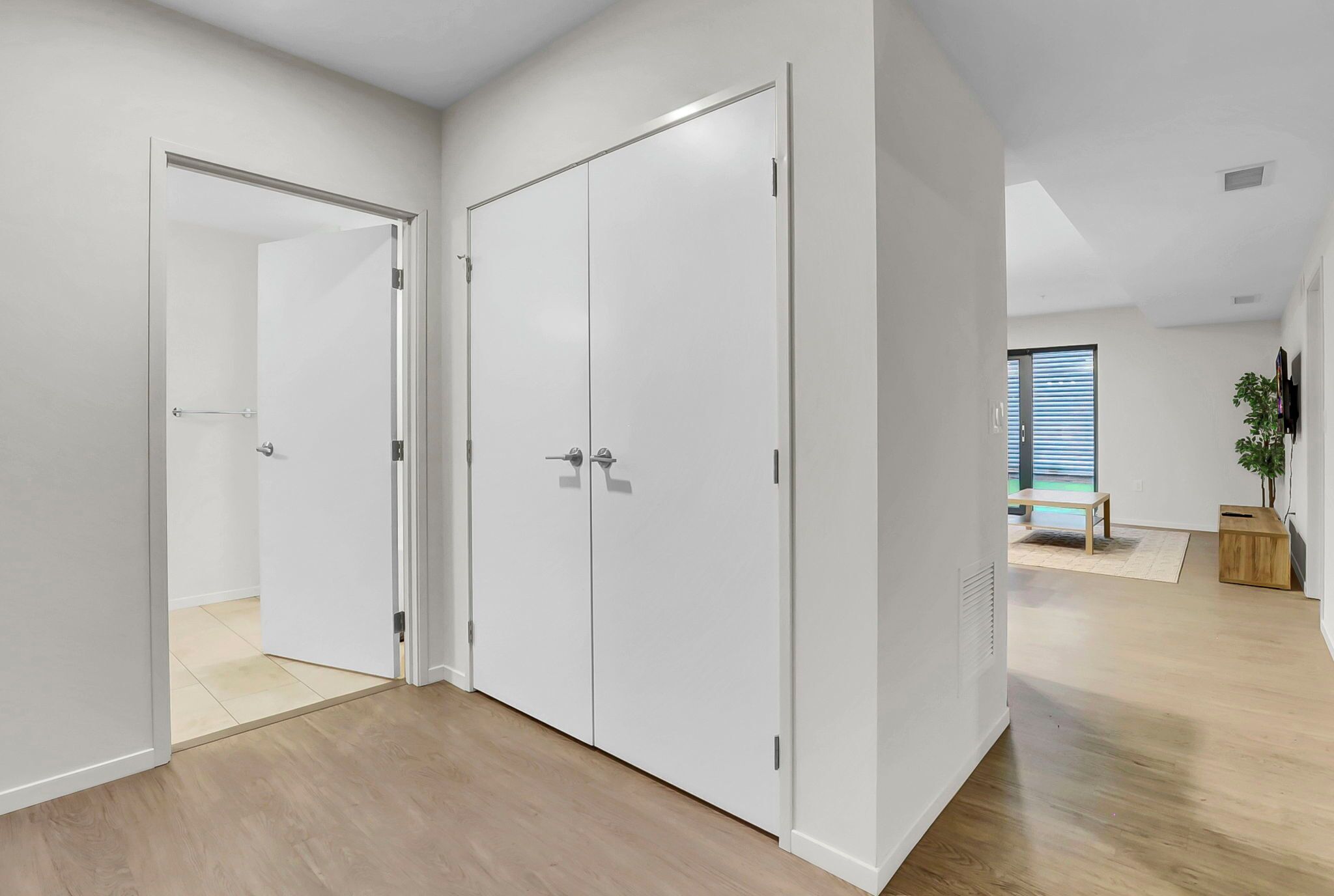 A modern room with a wooden floor, white walls, and a large wardrobe with two doors.